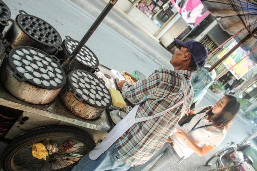 Tour of the Railway Market and Floating Market from Bangkok, Thailand. That's our tour guide buying us some delicious coconut pancakes from a street vendor before beginning our tour. #bangkok #thailand #railwaymarket #floatingmarket