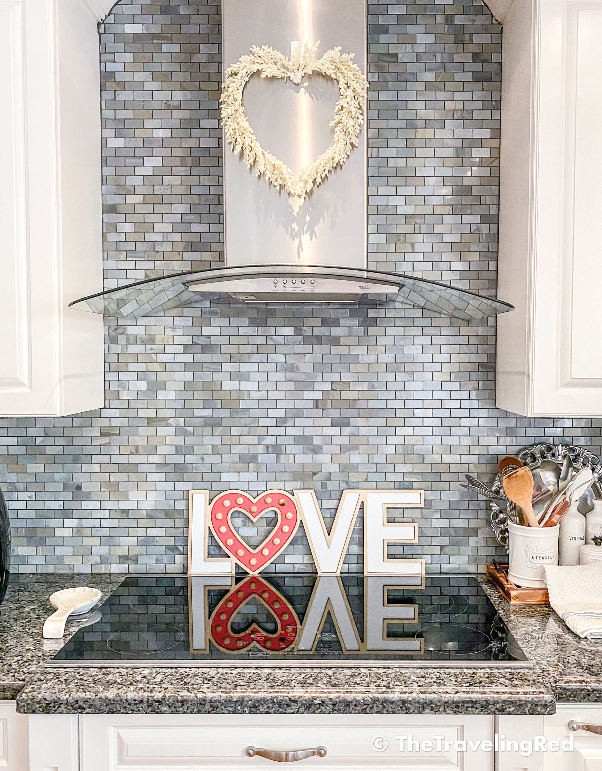 Valentine's Day Home Decor - Kitchen styling using a simple wh8ite heart wreath on my hood and a wood love sign behind the range - #valentinesday #valentinesdaydecor #homedecor #kitchendecor #valentinesdayhomedecor