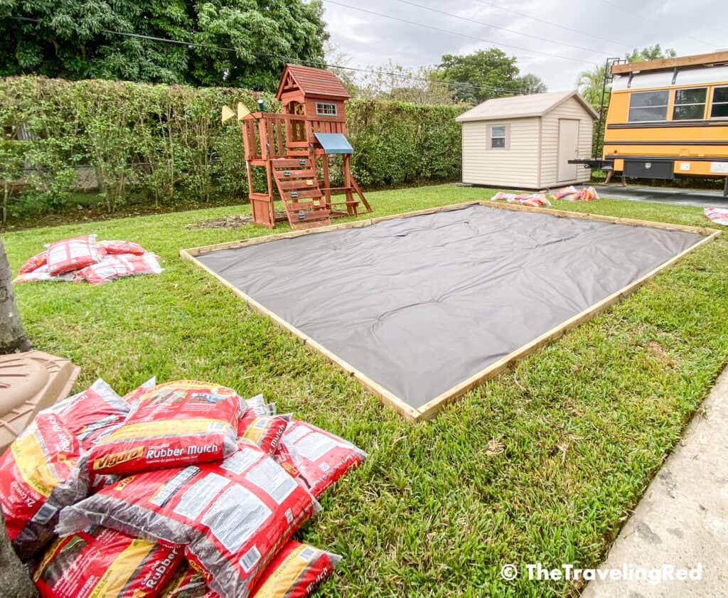 How to build a custom backyard playground with rubber mulch. Step 4 is to add a protective landscape barrier sheet to keep the weeds from growing out into the play area. This space will fit our swingset, playhouse, sandbox or any other outdoor toys you plan to include. Perfect little outdoor play space for your kids to enjoy playing outside.