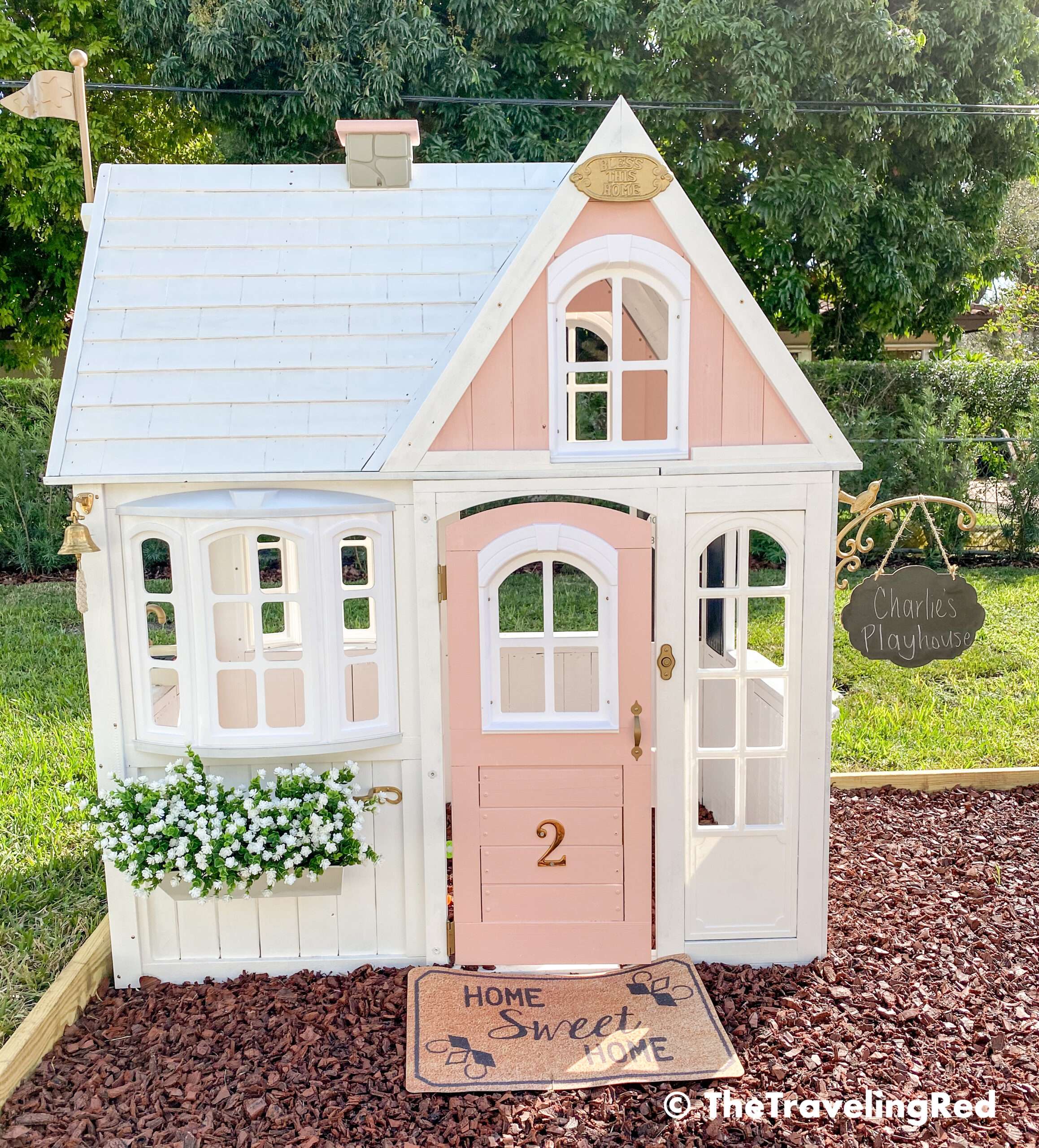 How we built a custom backyard playground with rubber mulch for our swingset, playhouse and sand box. Our playhouse was a store bought one that we renovated and turned into a little girls pink and white playhouse of her dreams. This outdoor playground is perfect little outdoor play space for your kids and it's soft on the feet.