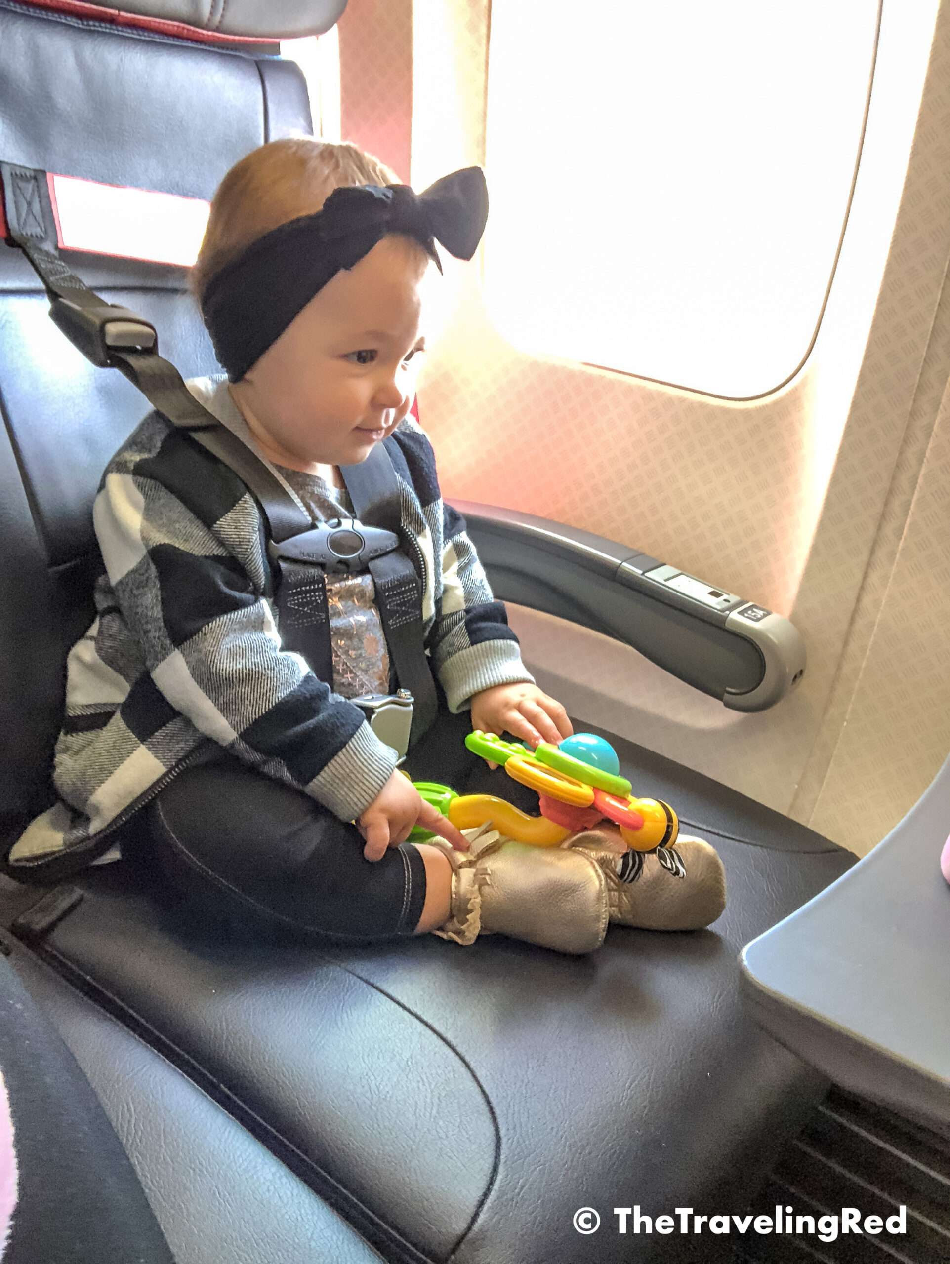 First time using her FAA approved airplane harness. It is an alternative to installing a car seat on an airplane. It it small and fits in your purse. The harness works with the airplane lap belt to restrain similar to a car seat. It does not affect the person sitting behind you because it goes under their tray table.