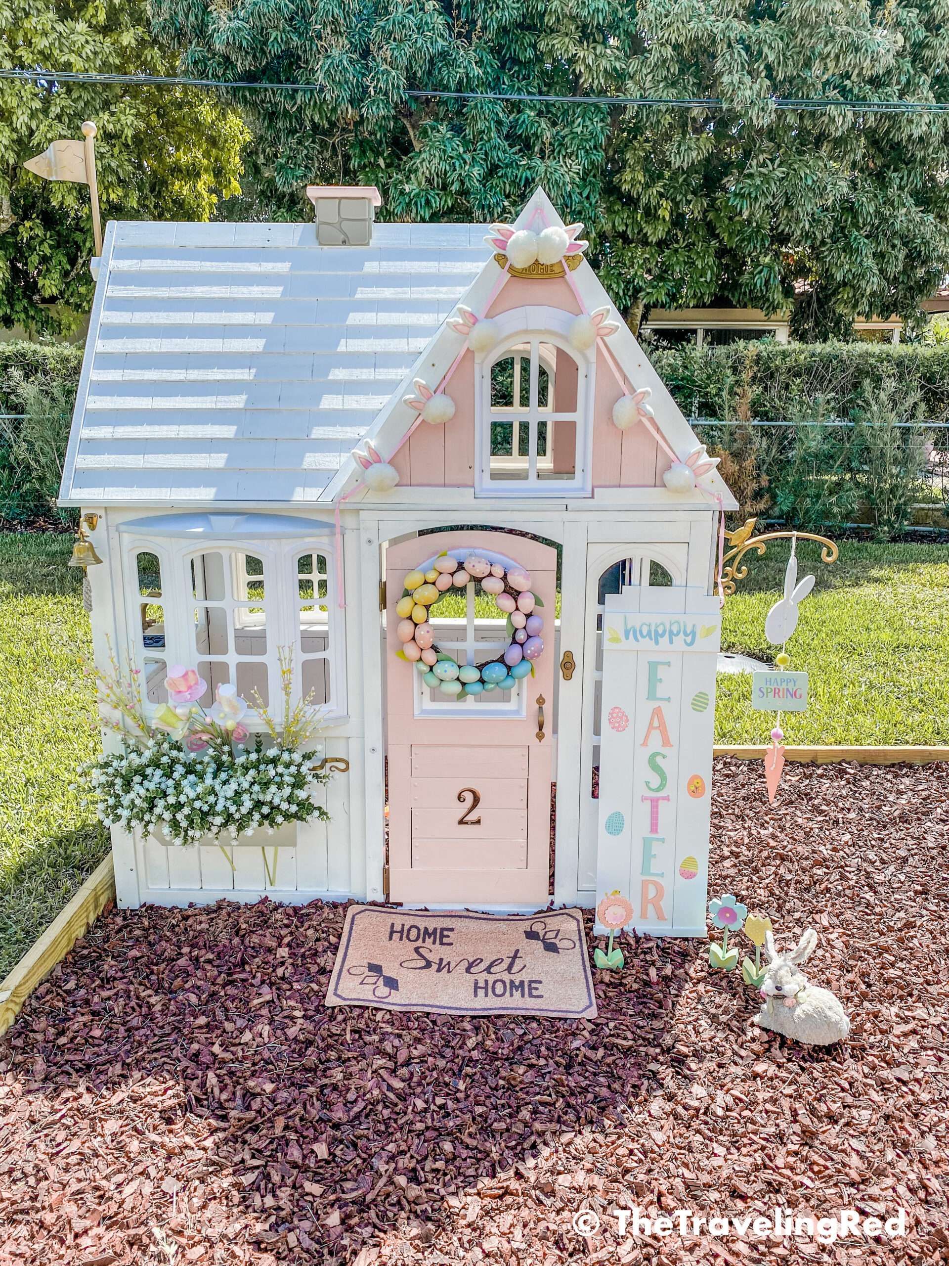 Little girls outdoor playhouse decorated for easter and spring. My daughters outdoor pink and white playhouse that my husband DIY ed for her custom backyard playground. It's the perfect backdrop for any photo shoot. I do seasonal photo shoots for each holiday in front of her house and decorate for the holiday.