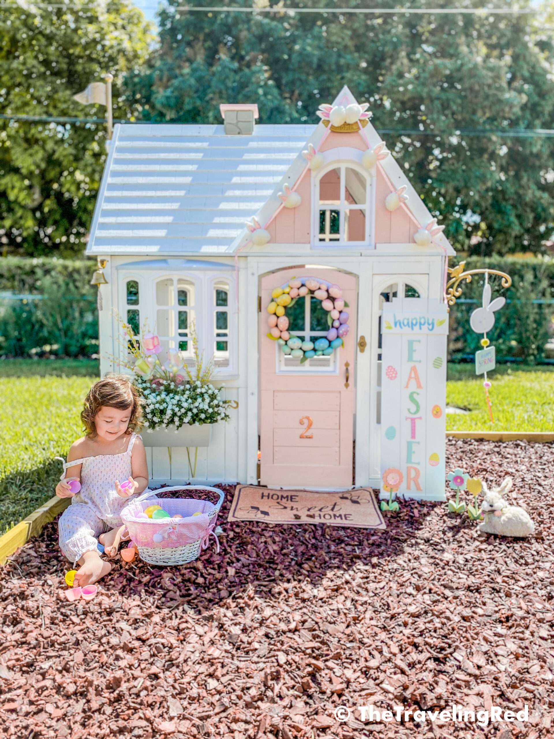 Little girls outdoor playhouse decorated for easter and spring. My daughters outdoor pink and white playhouse that my husband DIY ed for her custom backyard playground. It's the perfect backdrop for any photo shoot. I do seasonal photo shoots for each holiday in front of her house and decorate for the holiday.