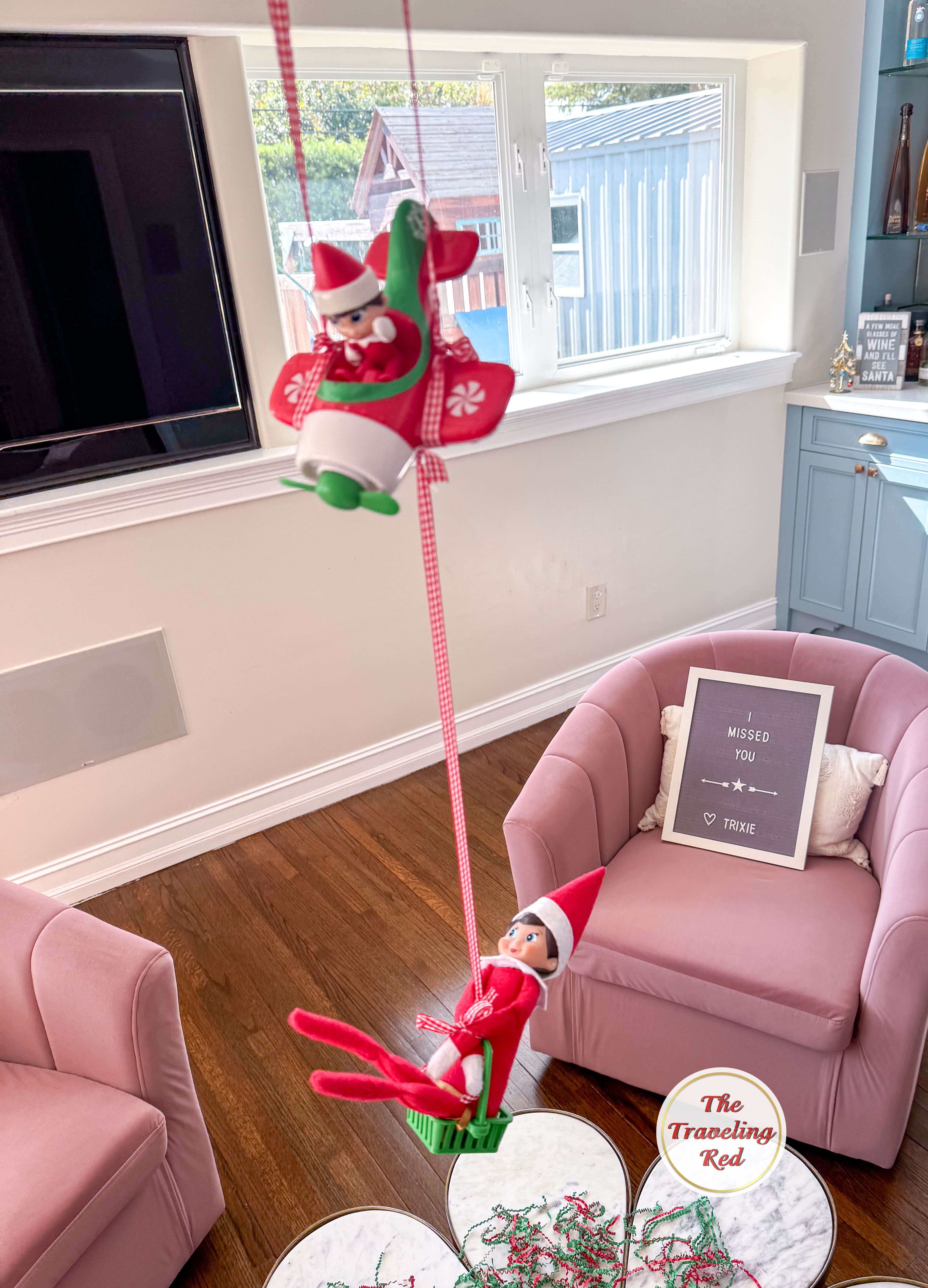Elf on the Shelf Ideas: Elf flying in on an elf on the shelf plane as her arrival. Over 100 easy and quick elf on the shelf ideas that are fun. By The Traveling Red