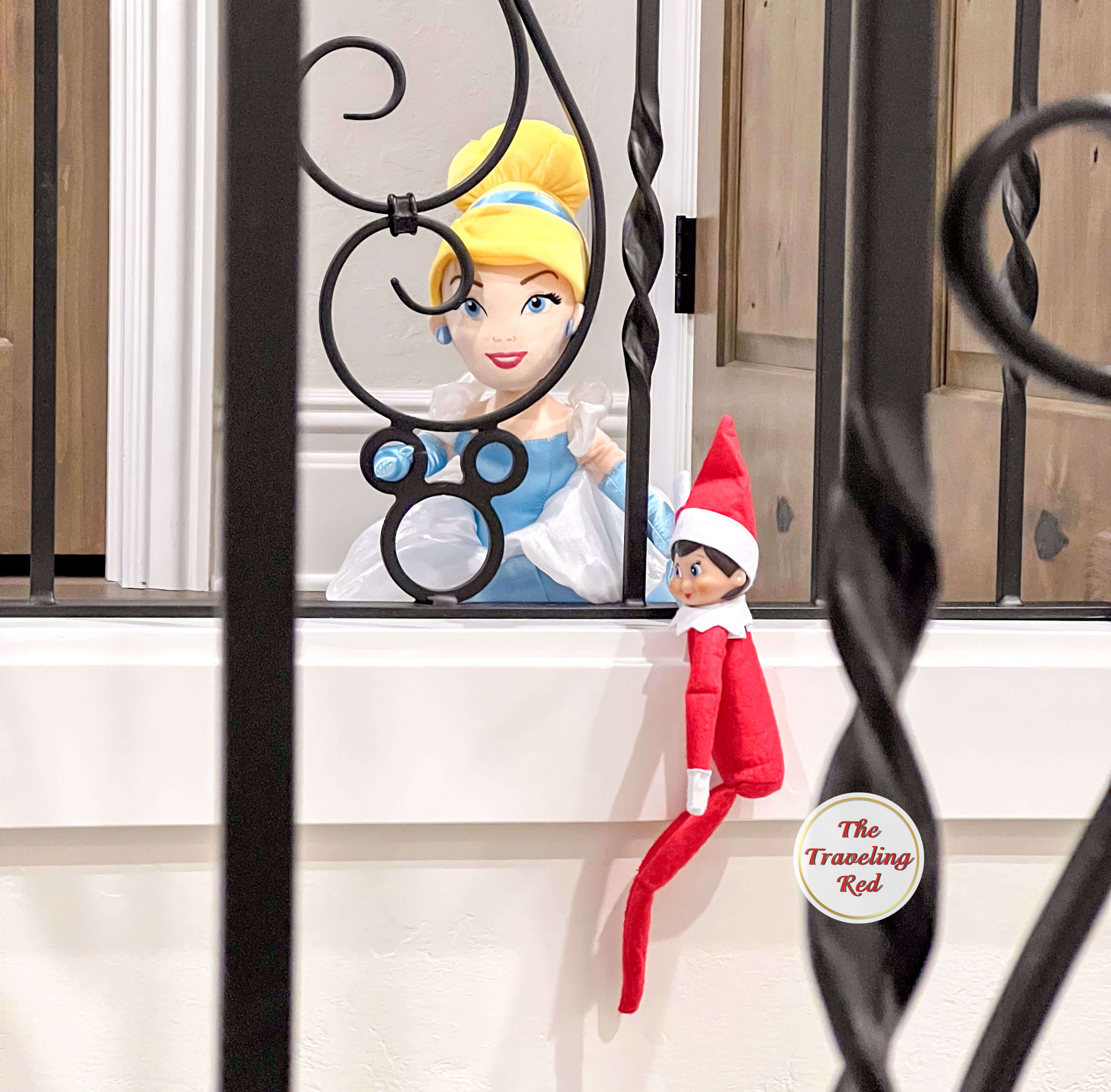 Elf on the Shelf Ideas: Elf is holding onto another dolls hand while suspended in the staircase. Over 100 easy and quick elf on the shelf ideas that are fun. By The Traveling Red