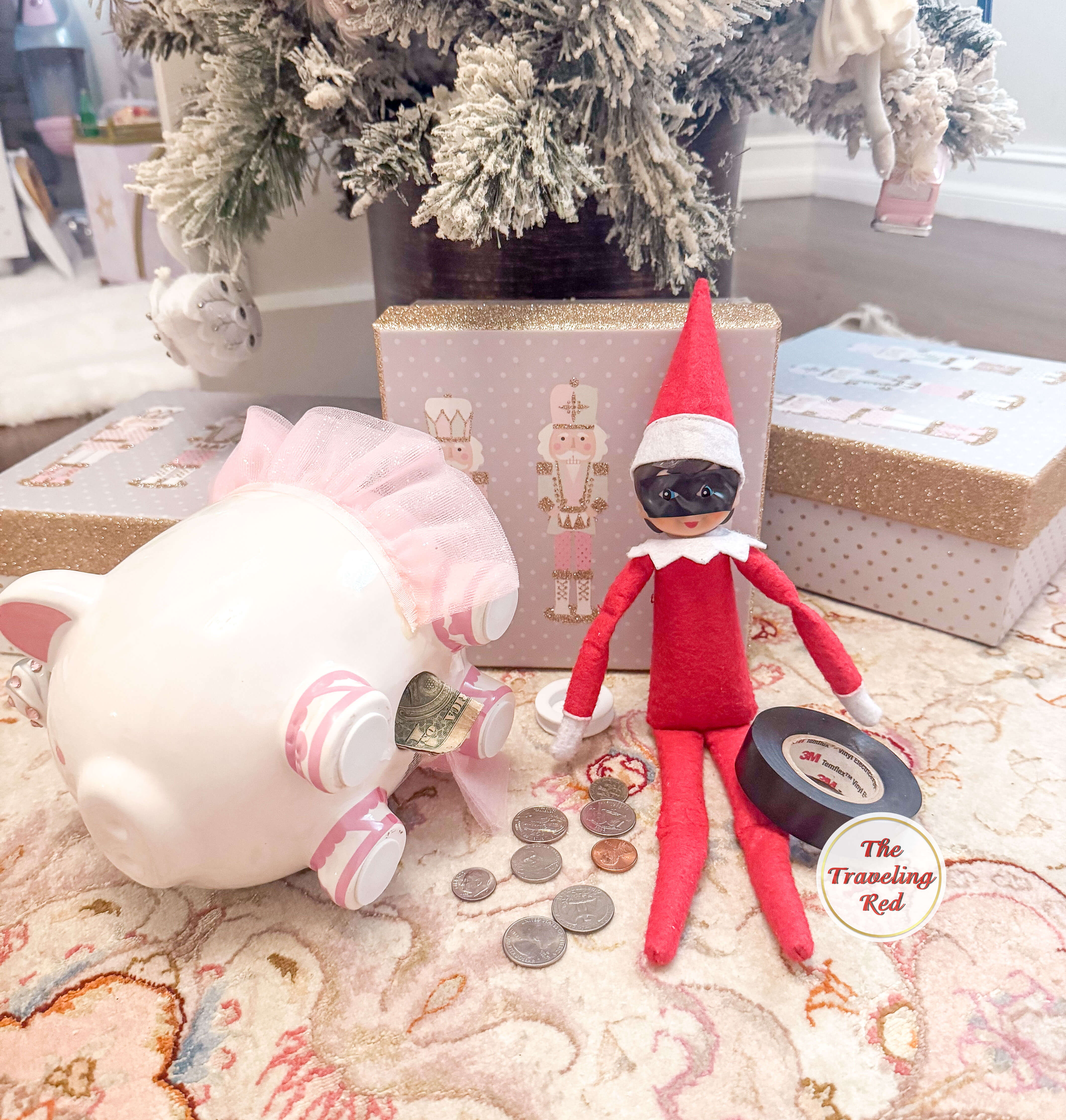 Elf on the Shelf Ideas: Elf is a piggy bank robber. Elf used 3M electrical tape to cover her face and cut out little holes for the eyes. The elf is placed next to the open piggy bank with some change on the floor. Over 100 easy and quick elf on the shelf ideas that are fun. By The Traveling Red