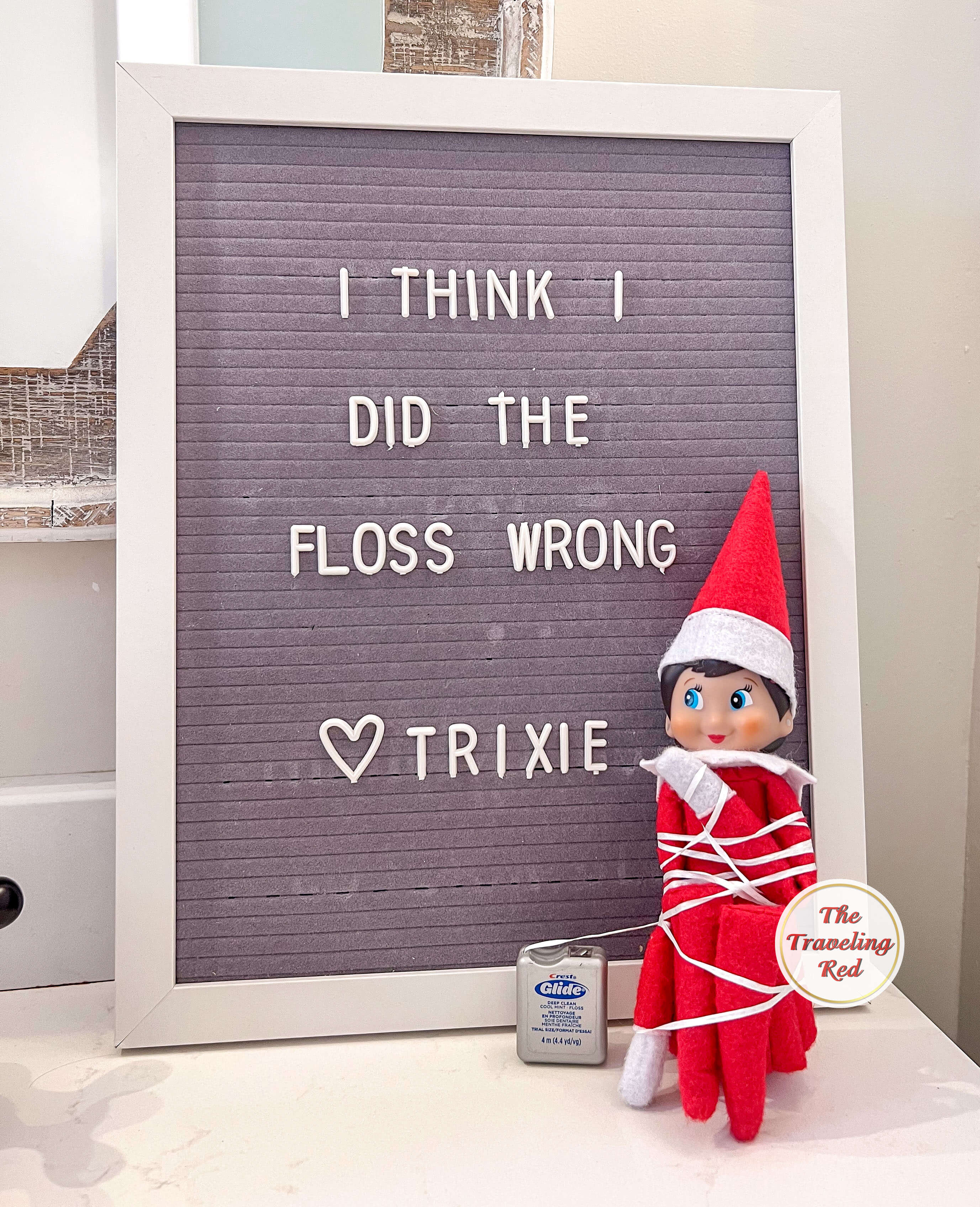 Elf on the Shelf Ideas: Elf is tied up in floss and the message board reads I think I did the floss wrong. Over 100 easy and quick elf on the shelf ideas that are fun. By The Traveling Red