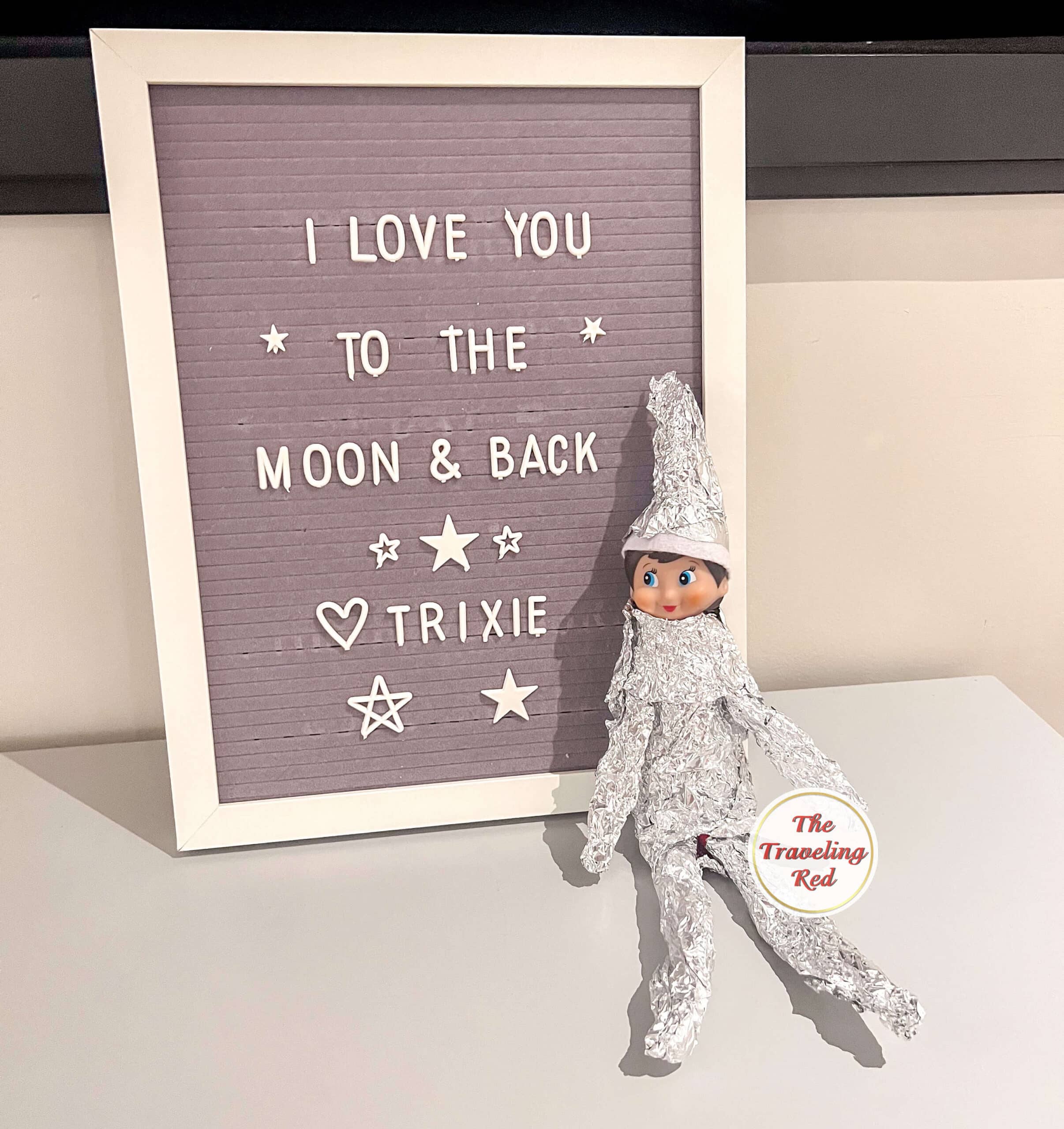 Elf on the Shelf Ideas: Elf is wrapped in tin foil to look like an astronaut and the message reads "I love you to the moon and back". Over 100 easy and quick elf on the shelf ideas that are fun. By The Traveling Red