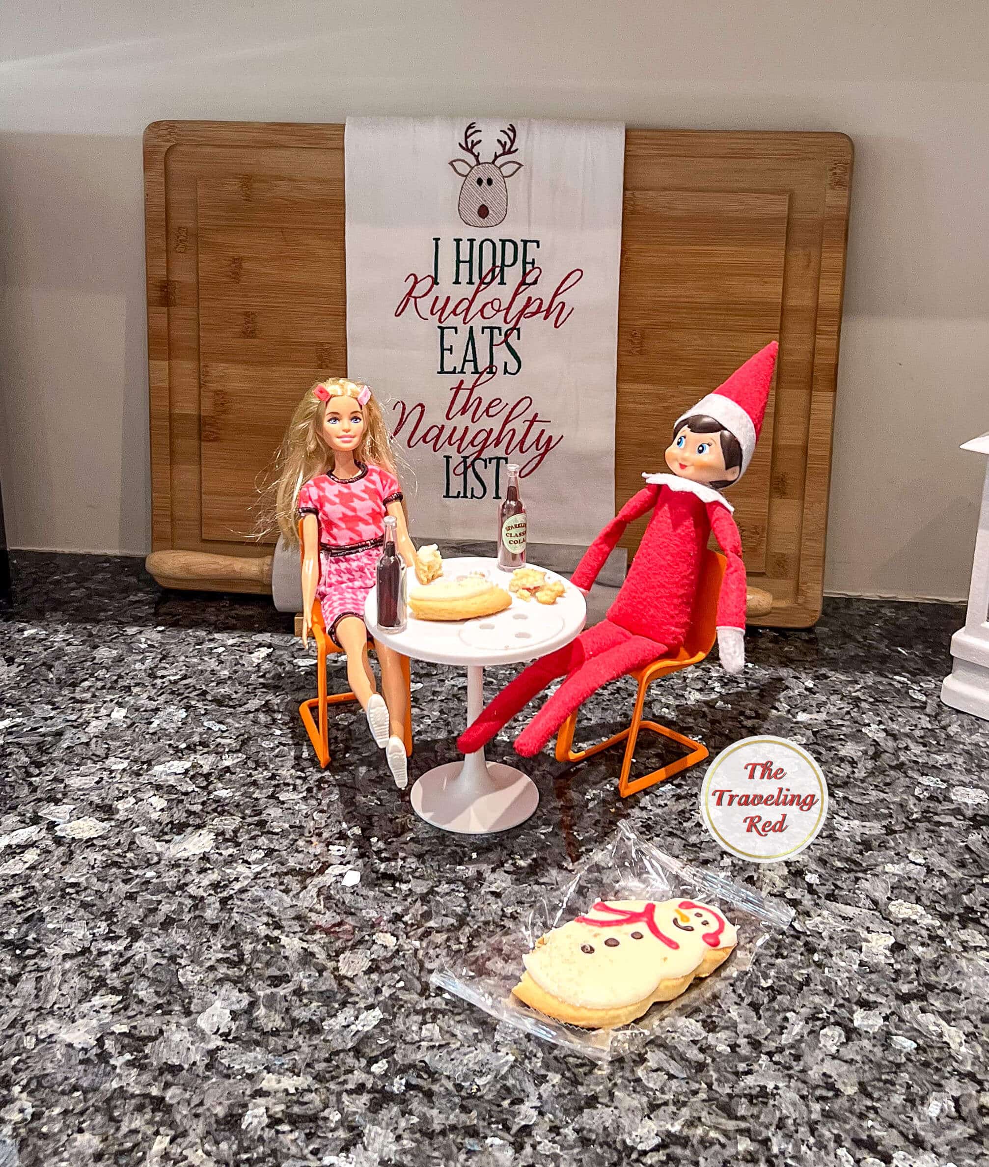 Elf on the Shelf Ideas: Elf is having brunch with a barbie at a barbie house table. Over 100 easy and quick elf on the shelf ideas that are fun. By The Traveling Red