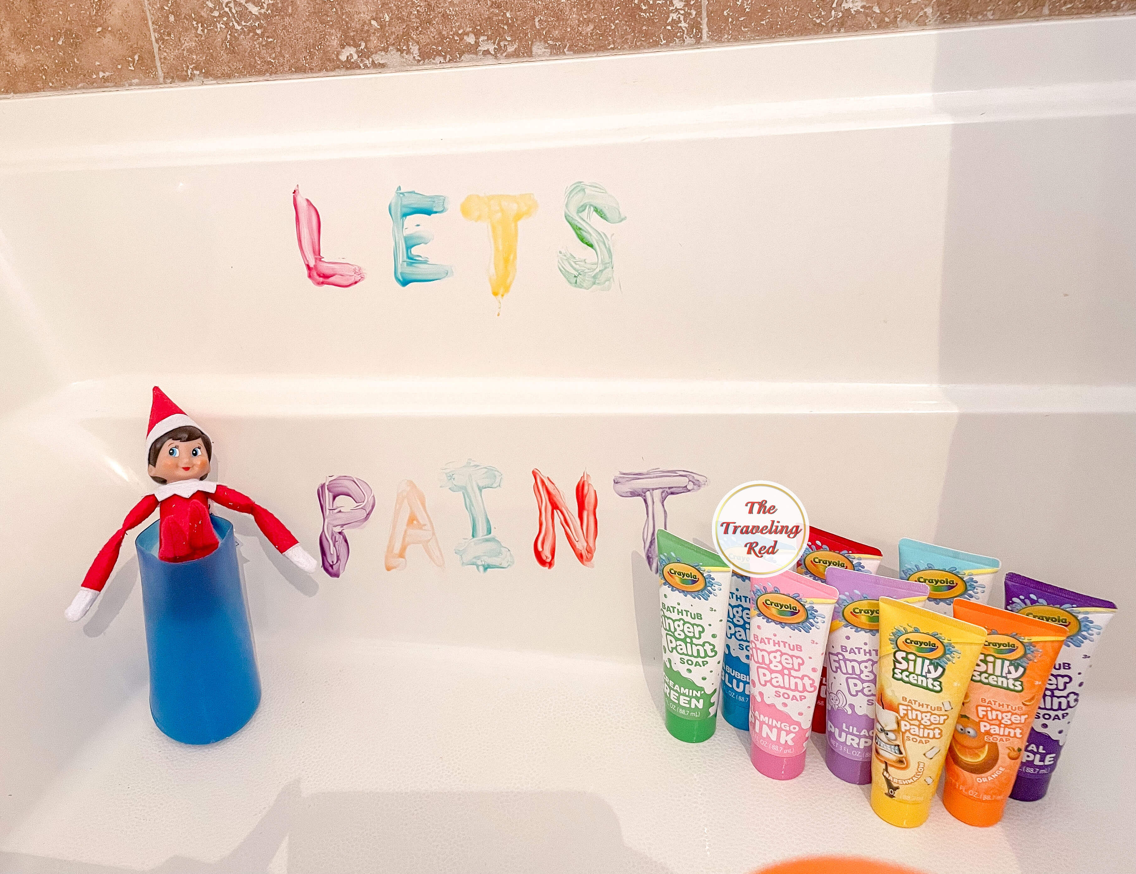 Elf on the Shelf Ideas: Elf is in the water bucket in the bathtub next to bath paints and used the bath paints to write lets paint on the tub. Over 100 easy and quick elf on the shelf ideas that are fun. By The Traveling Red