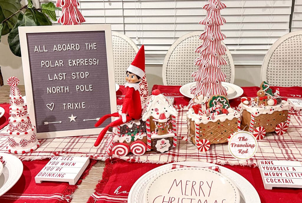 Elf on the Shelf Ideas: Elf is sitting on the decorative Christmas train and the message board say "All Aboard the Polar Express. Last stop North Pole". Over 100 easy and quick elf on the shelf ideas that are fun. By The Traveling Red