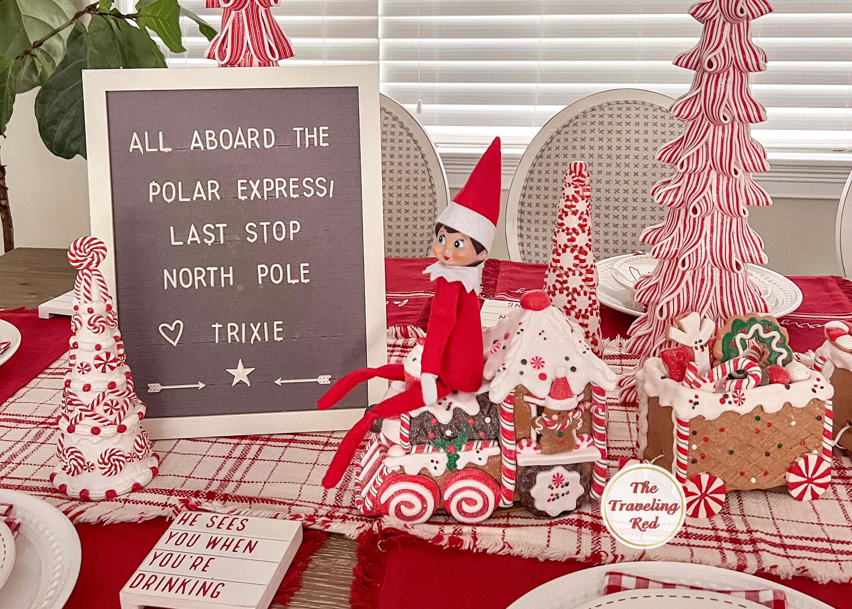 Elf on the Shelf Ideas: Elf is sitting on the decorative Christmas train and the message board say "All Aboard the Polar Express. Last stop North Pole". Over 100 easy and quick elf on the shelf ideas that are fun. By The Traveling Red