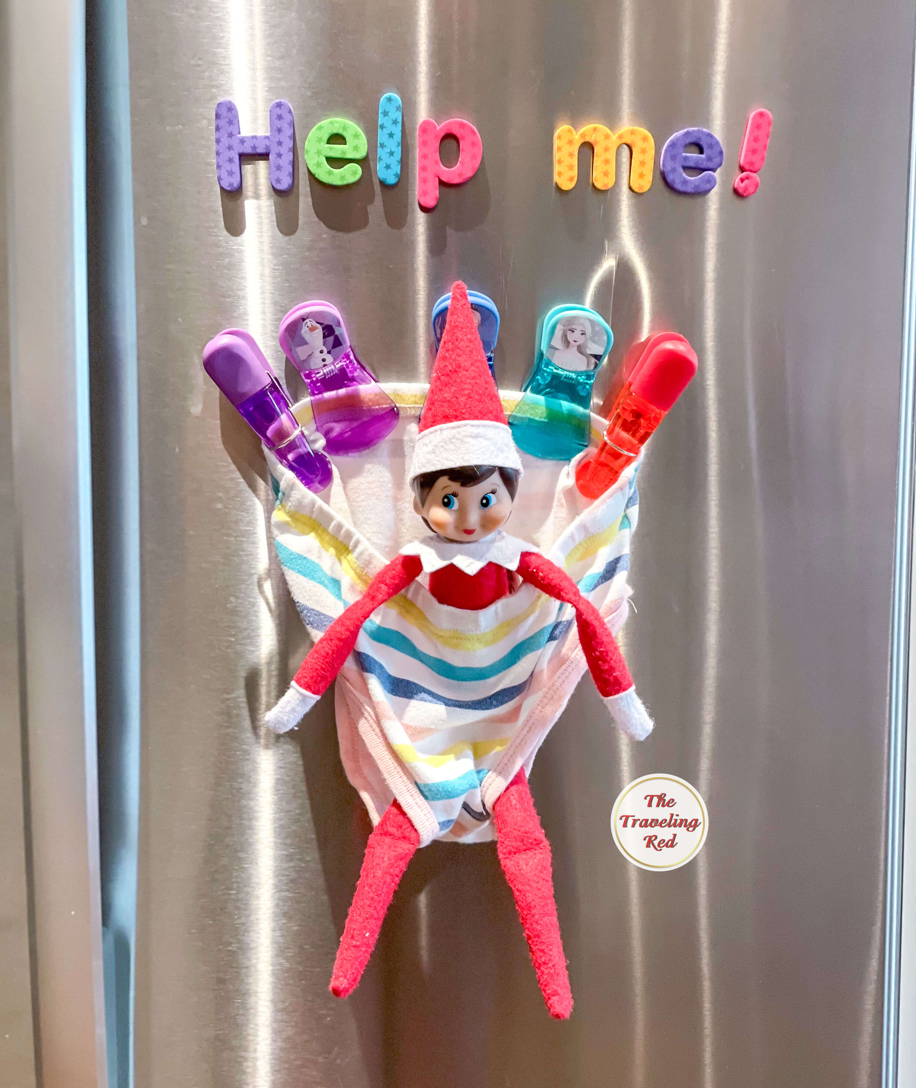 Elf on the Shelf Ideas: Elf is stuck in an underwear attached to the fridge with magnets and magnetic letters spelling out help me above it. Over 100 easy and quick elf on the shelf ideas that are fun. By The Traveling Red