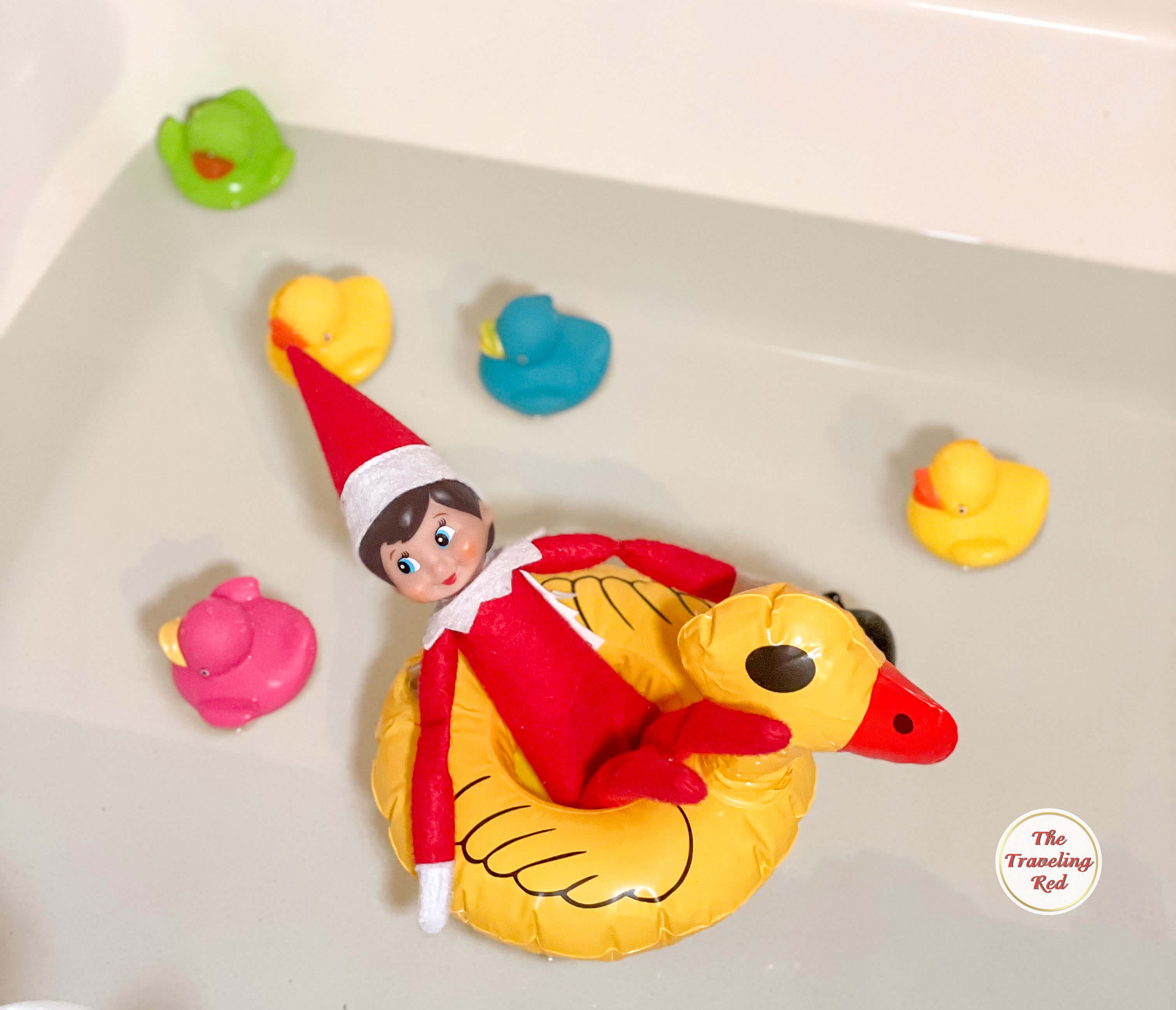 Elf on the Shelf Ideas: Elf is in the bathtub on a duck drink float with little rubber ducks floating around it. Over 100 easy and quick elf on the shelf ideas that are fun. By The Traveling Red
