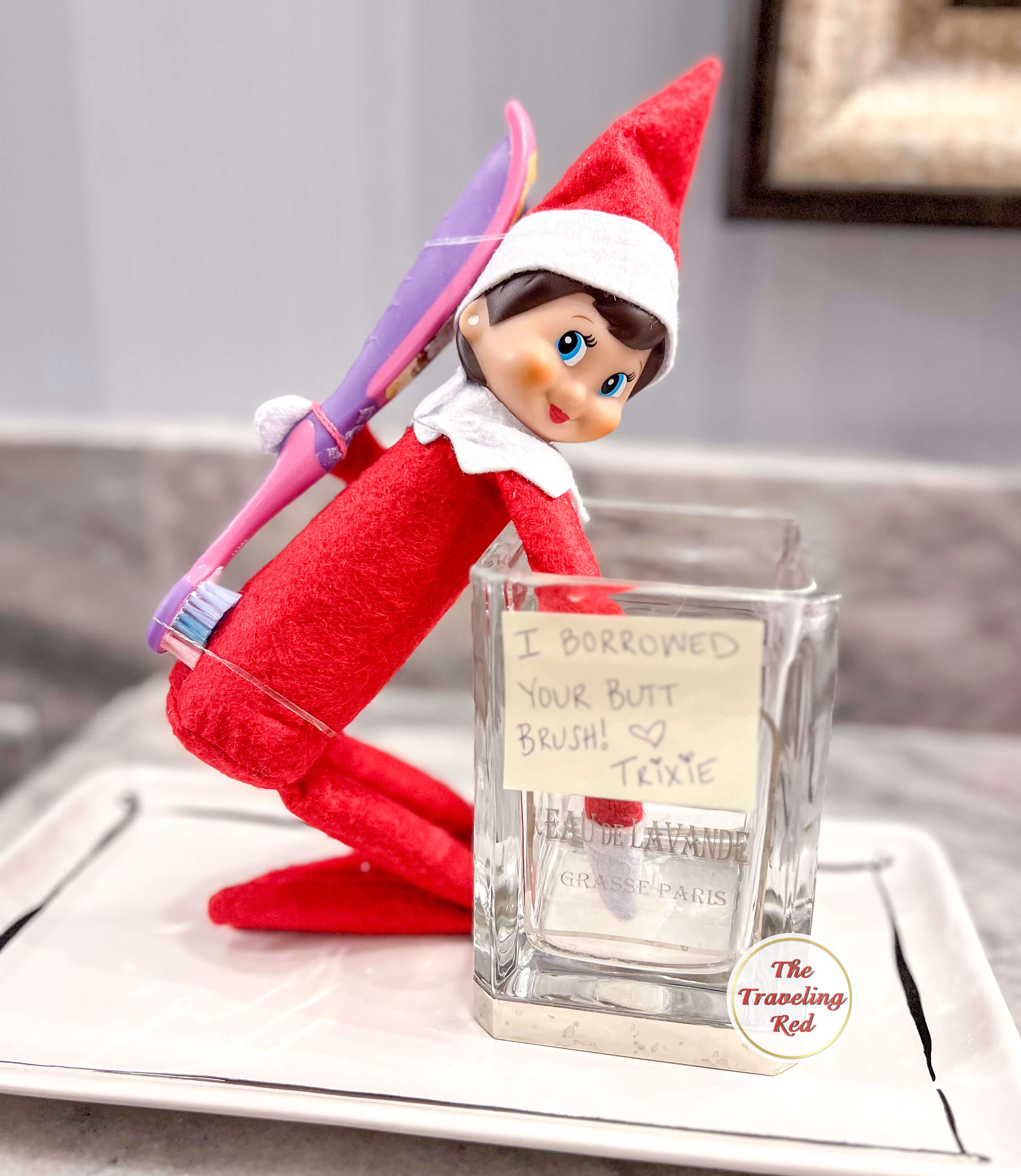 Elf on the Shelf Ideas: Elf is kneeling with a toothbrush attached to its back and a note saying thank you for letting me borrow your butt brush. Over 100 easy and quick elf on the shelf ideas that are fun. By The Traveling Red