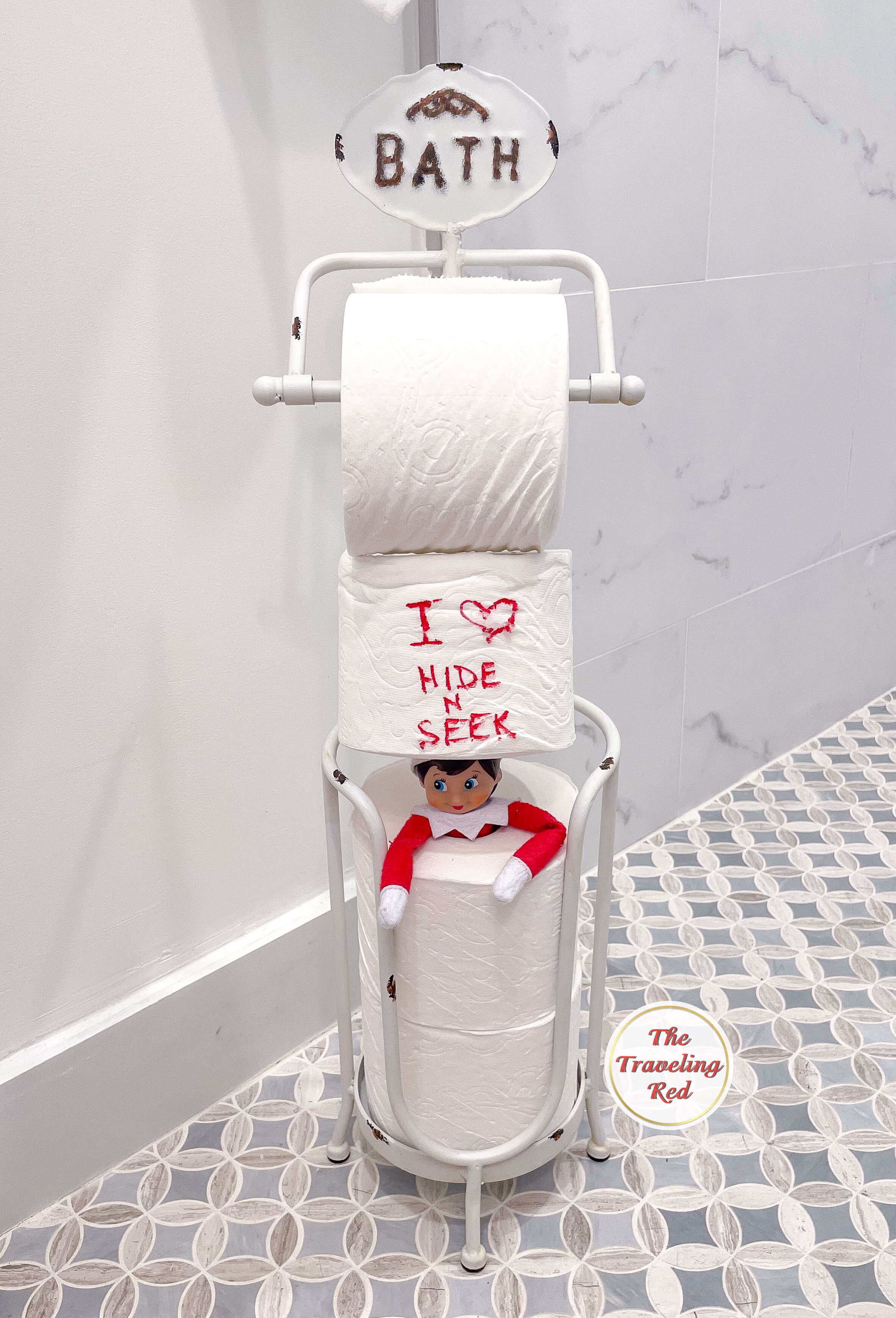 Elf on the Shelf Ideas: Elf is playing hide and seek and hiding in a stack of toilet paper rolls. Over 100 easy and quick elf on the shelf ideas that are fun. By The Traveling Red