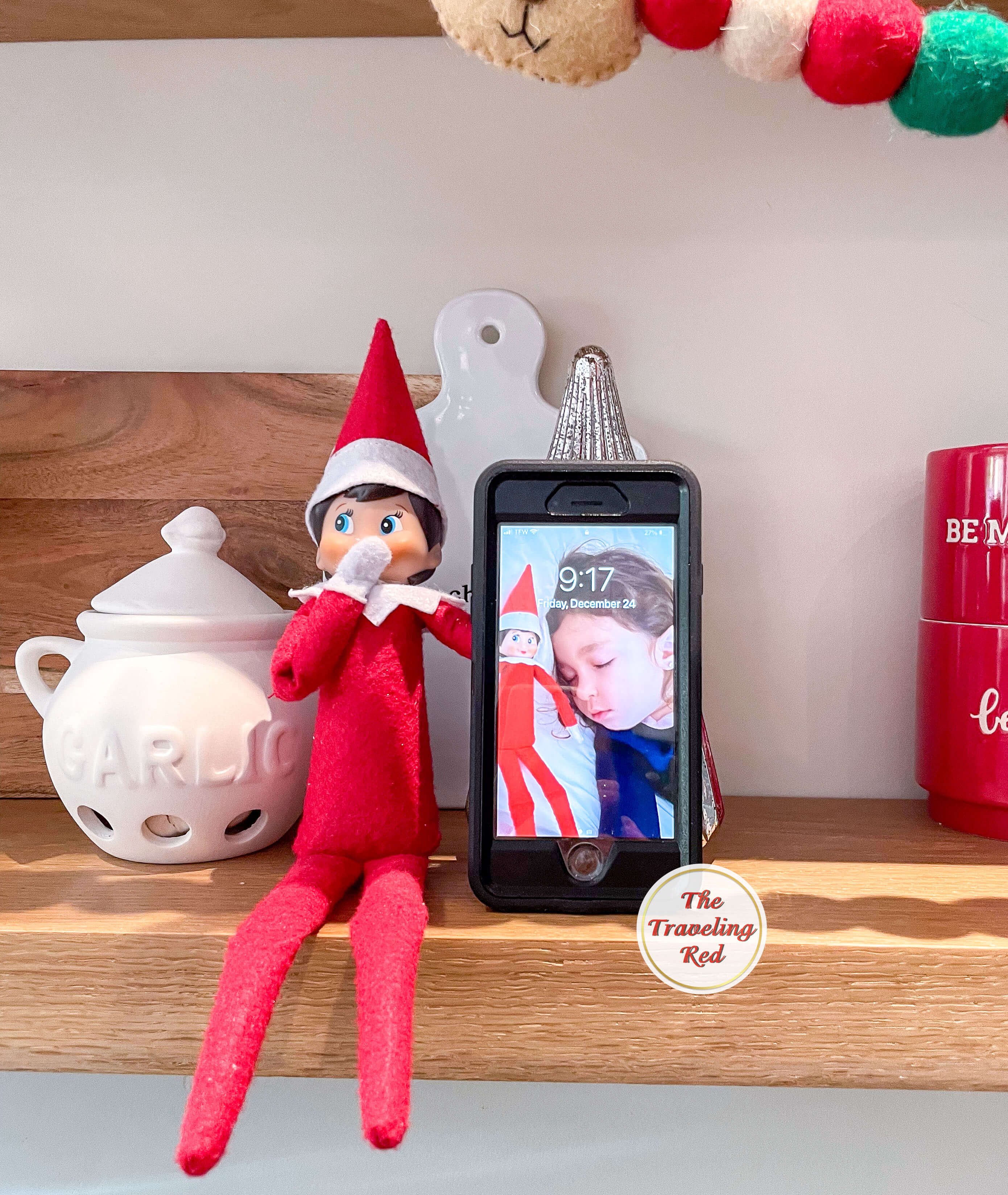 Elf on the Shelf Ideas: Elf took a photo of herself next to the sleeping child then made it the lock screen on the phone. In the morning the elf is sitting next to the phone on a shelf. Over 100 easy and quick elf on the shelf ideas that are fun. By The Traveling Red