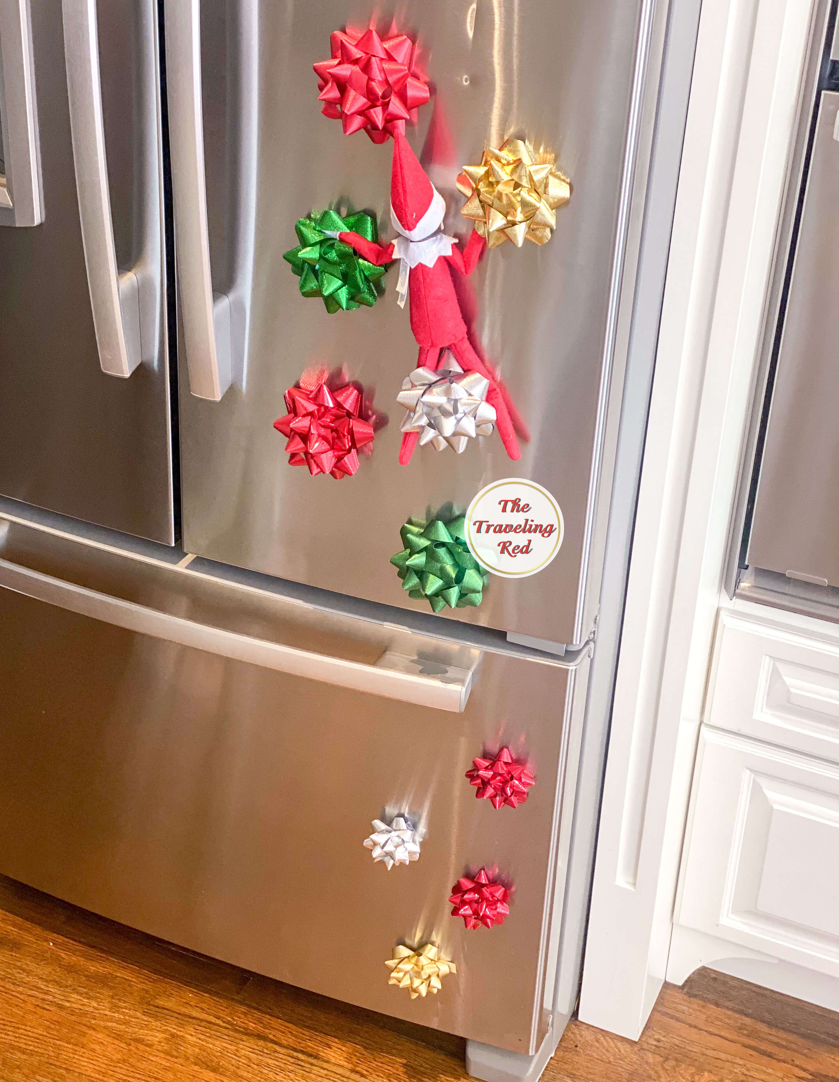 Elf on the Shelf Ideas: Elf is climbing up the fridge using wrapping bows as the rocks for rockclimbing. Over 100 easy and quick elf on the shelf ideas that are fun. By The Traveling Red