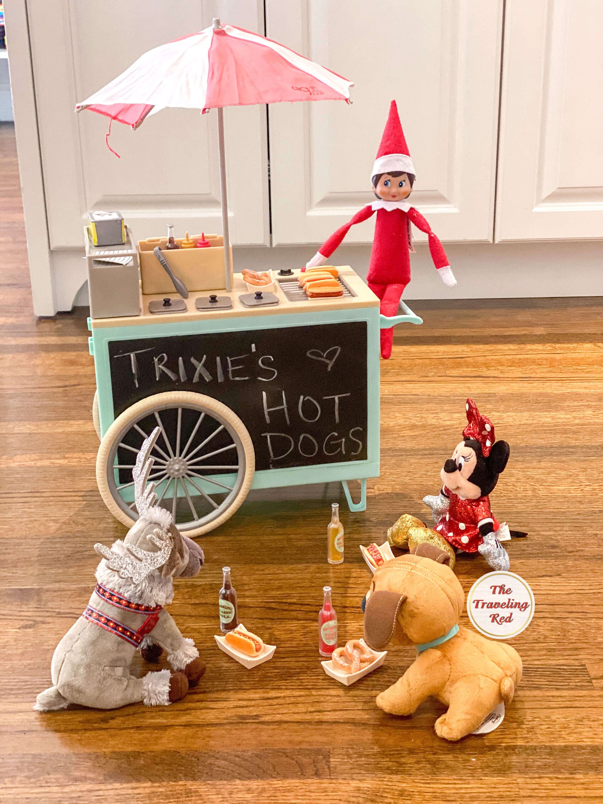 Elf on the Shelf Ideas: Elf got a doll hot dog cart and set it up for other toys and friends. Over 100 easy and quick elf on the shelf ideas that are fun. By The Traveling Red